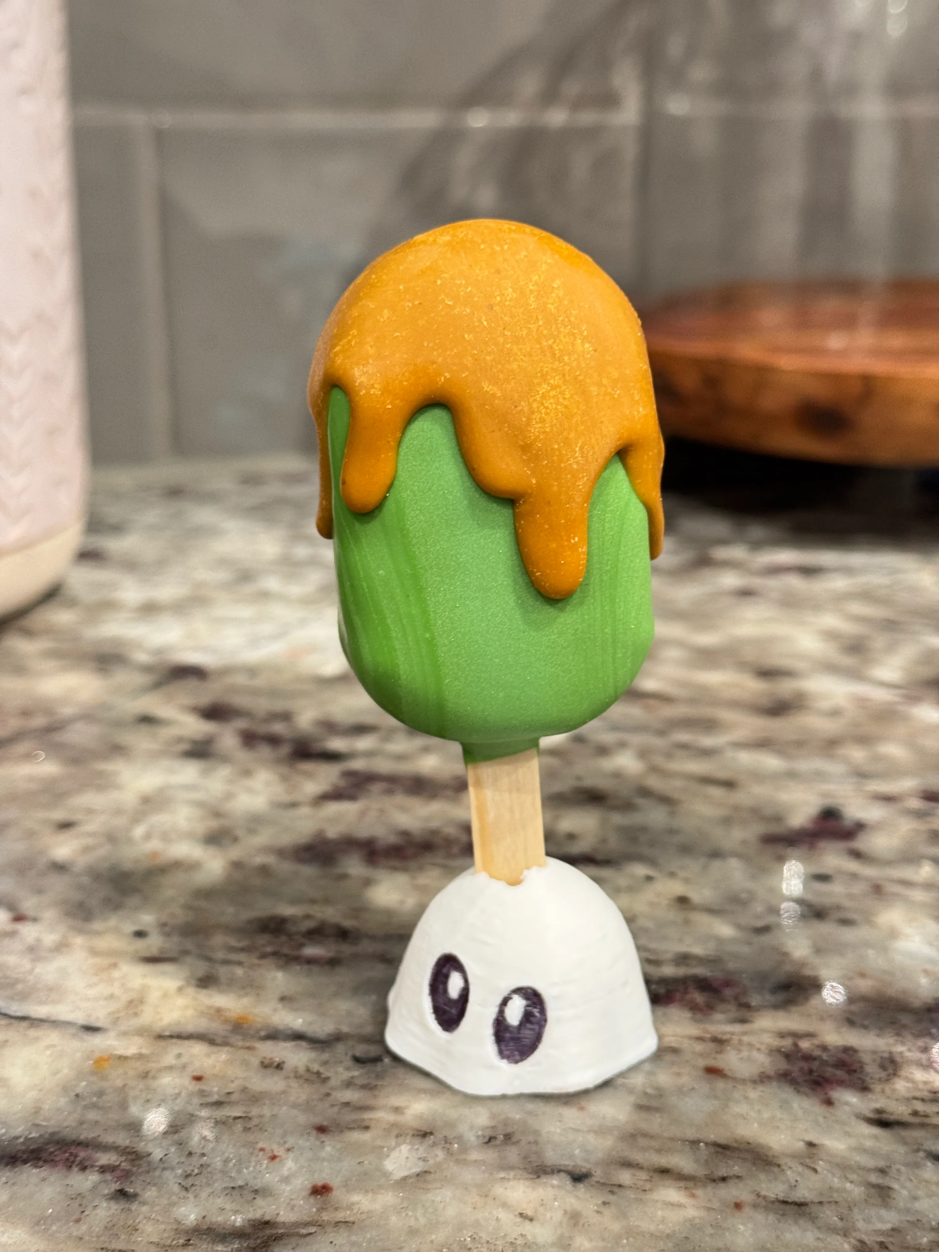 Caramel apple cakesicle in a green shell with caramel dripping down from the top