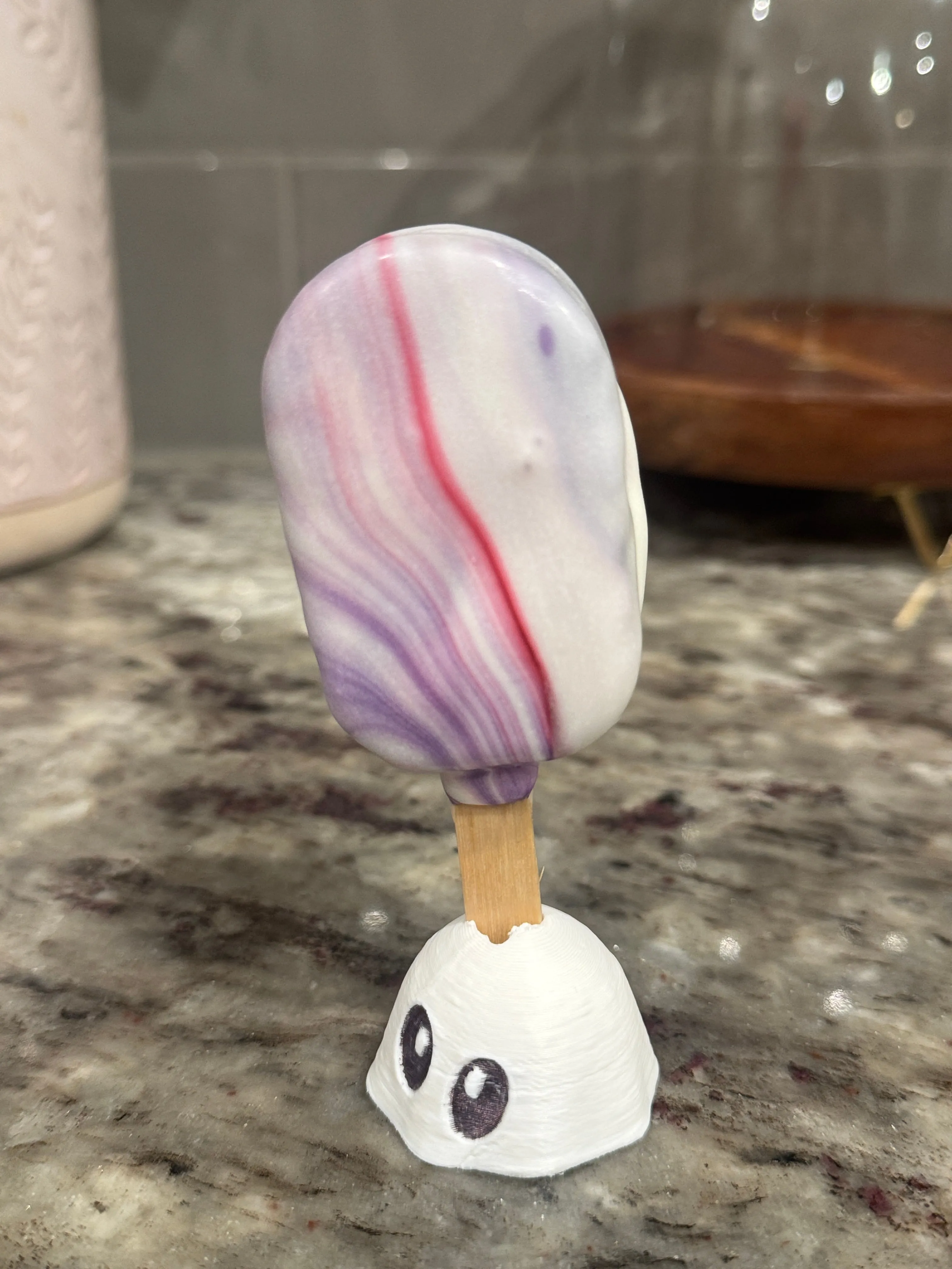 Cakesicle with soft purple and pink marbling on a white shell