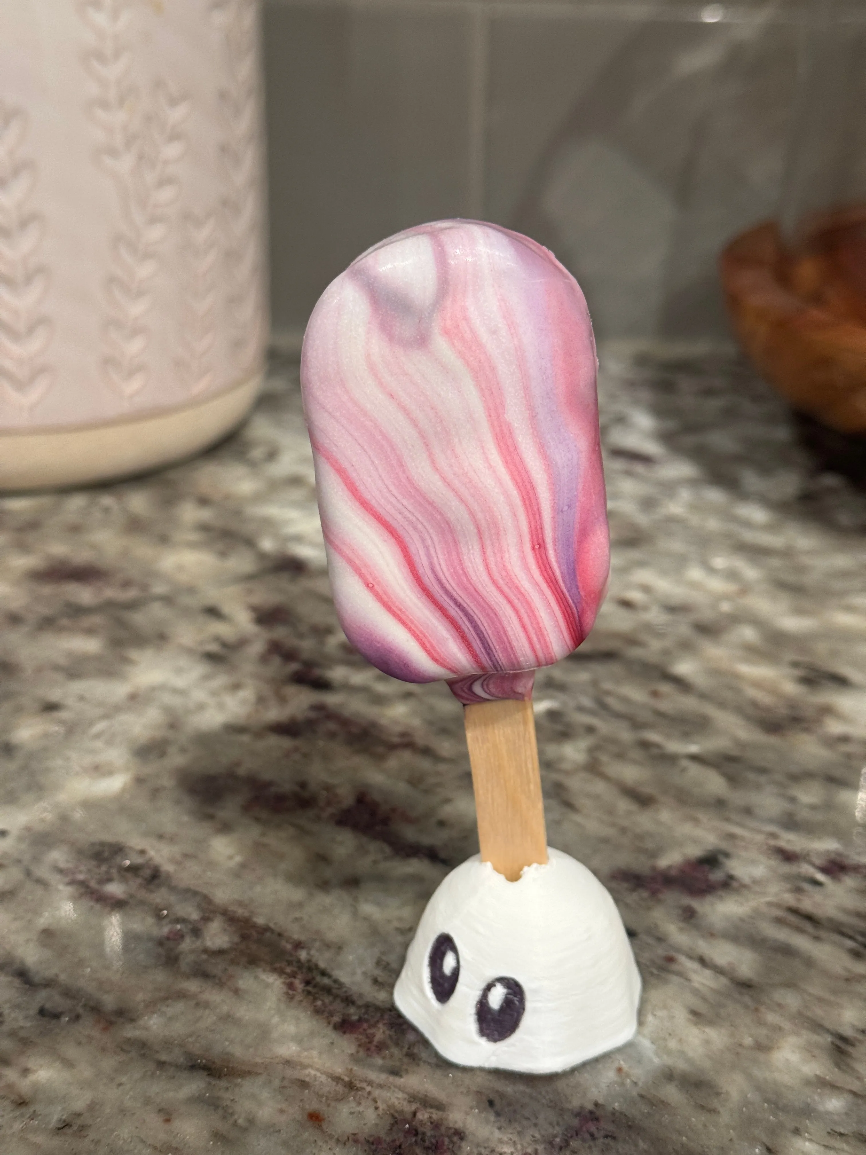 Cakesicle with dense pink and purple marbling swirled through a white shell
