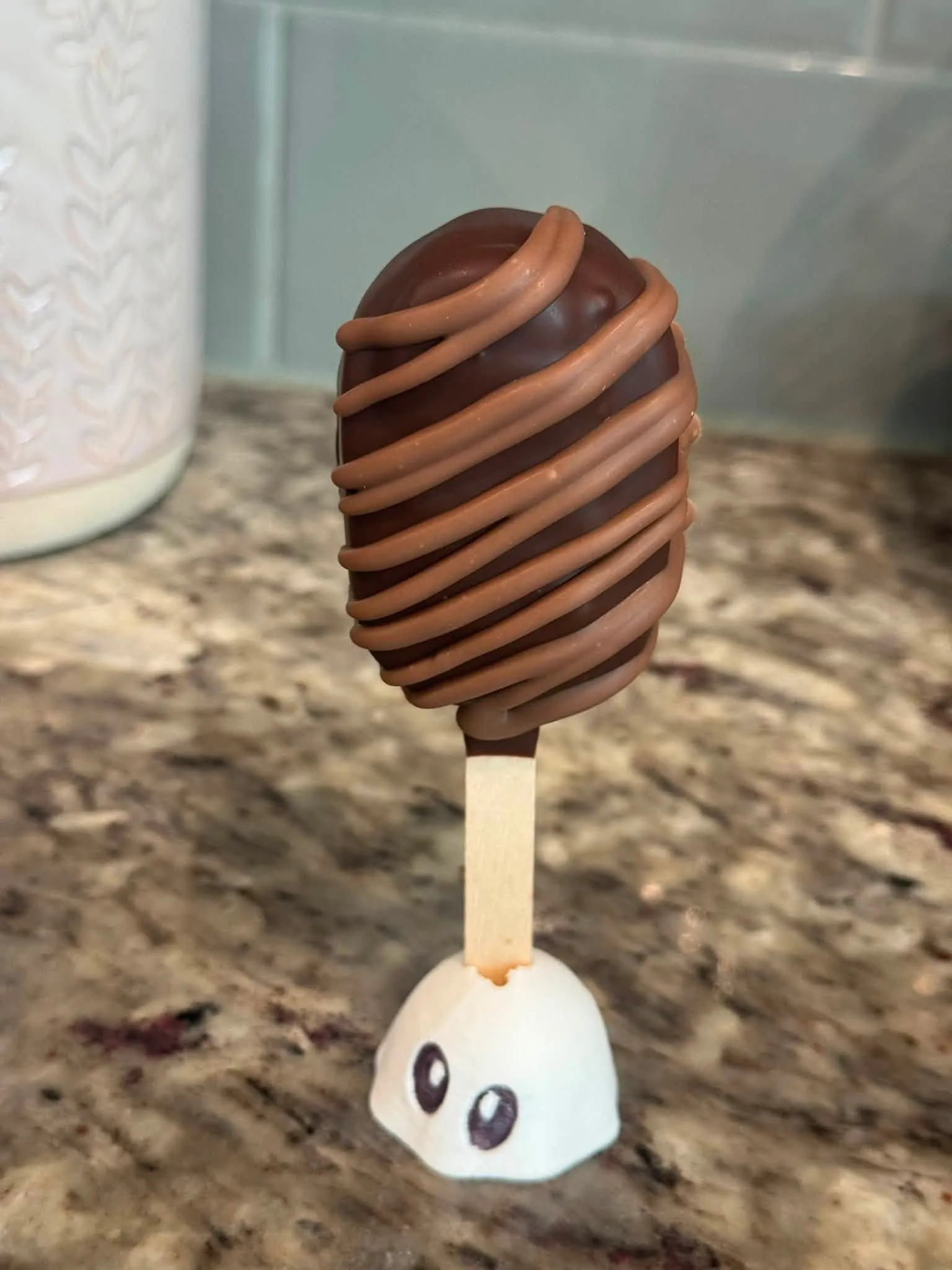 Milky Way cakesicle in a dark chocolate shell with a milk chocolate drizzle