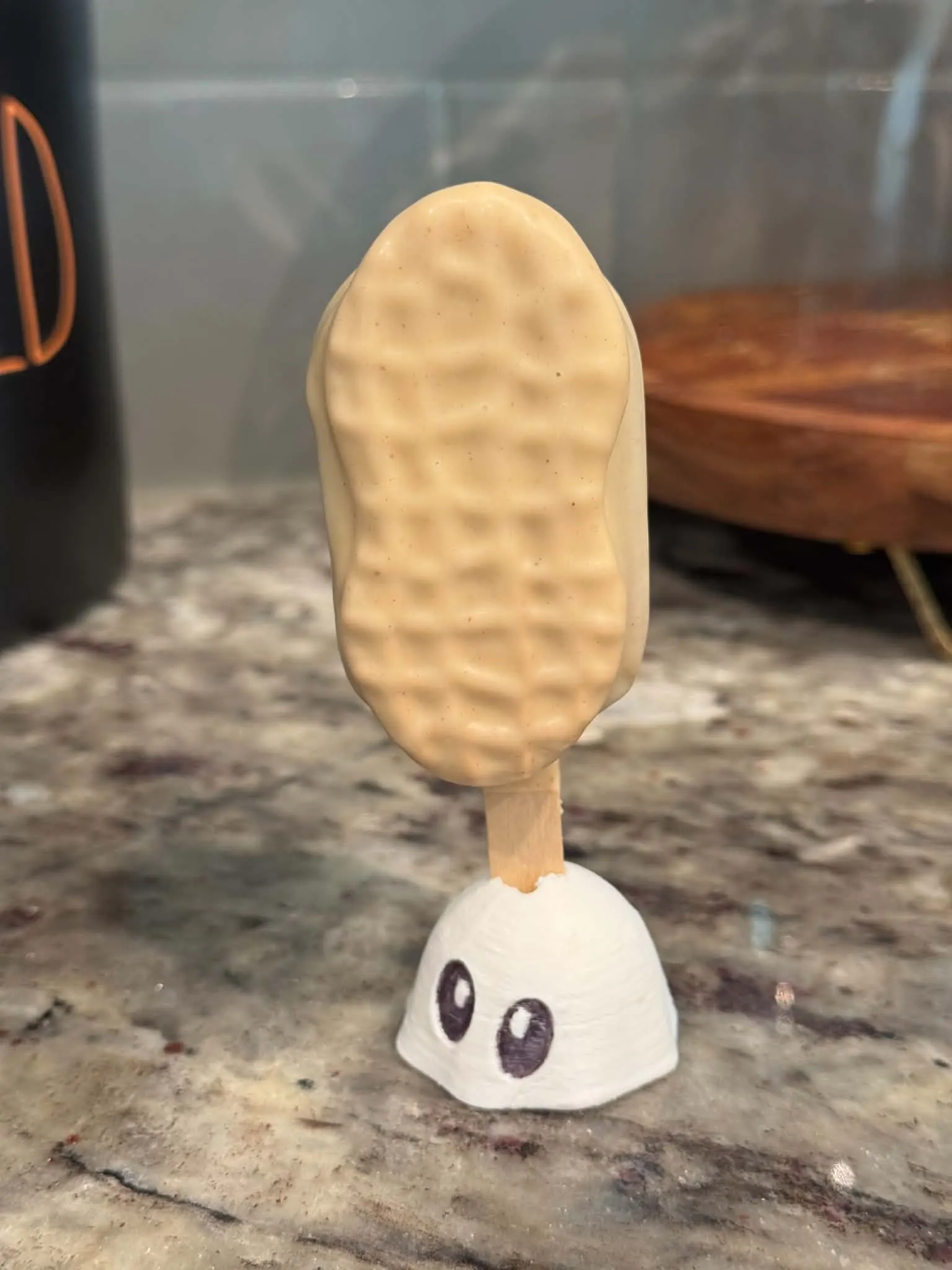 Nutter Butter cakesicle shaped and textured like a peanut-shaped sandwich cookie, in a tan peanut butter shell